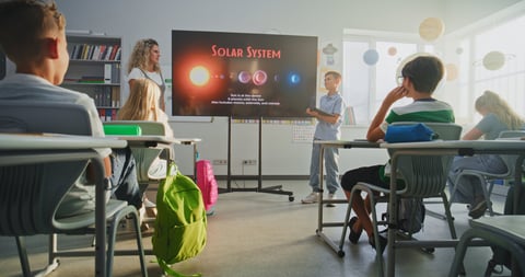 Elementary School Boy with Tablet Computer Giving Presentation About Solar System and Planets in Front of Classmates and Teacher Using Digital Screen. Smart Kids Studying Space Astronomy in Classroom.